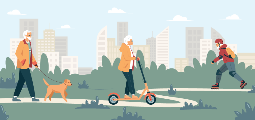 An active senior woman rides a kick scooter along a winding park path with city buildings in the background, demonstrating independence